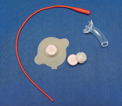 Red rubber tube, base plate with a heat and moisture exchanger, and a laryngectomy tube.