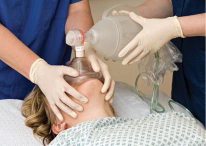 Two people ventilating a patient with a bag valve mask.